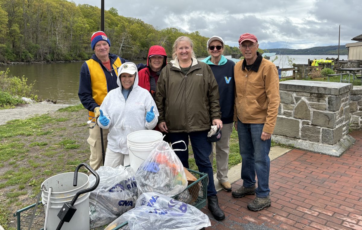 Six volunteers stand behind a cart filled with trash.