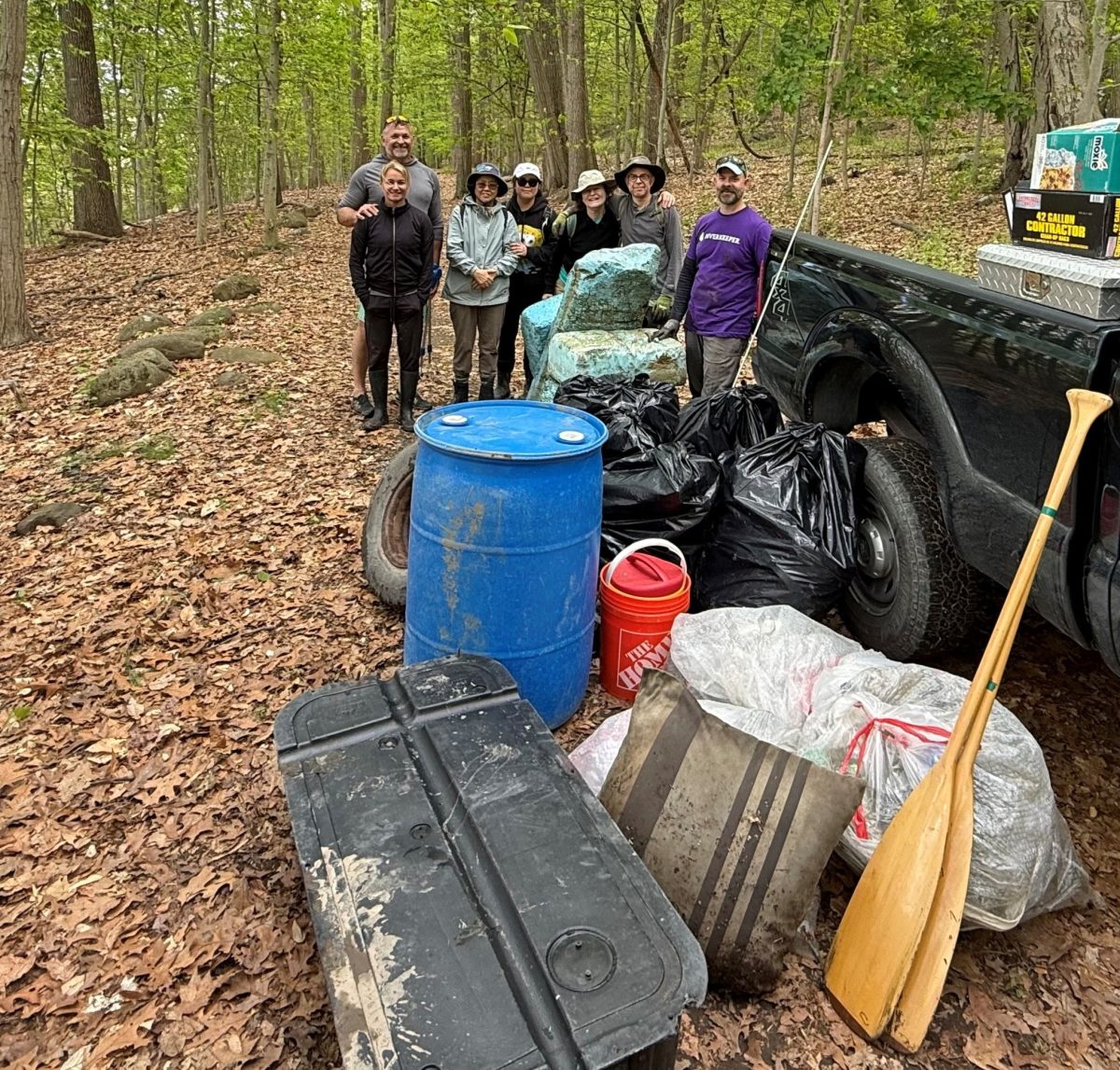 Seven people stand behind a pile of trash and debris.